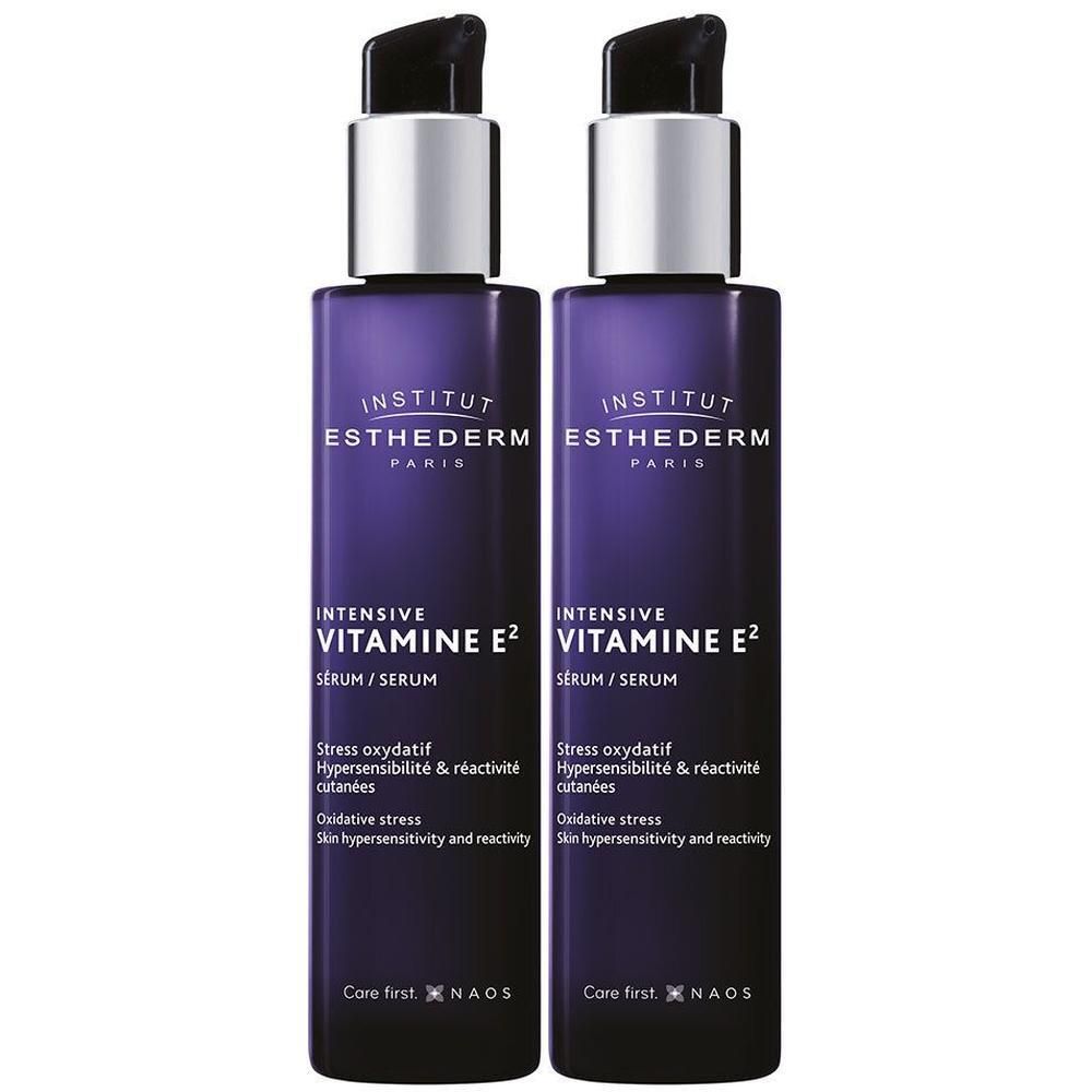Deux flacons de sérum INSTITUT ESTHEDERM Intensiv-Vitamin E2. Flacons violets avec pompes argentées. Texte: Intensiv Vitamin E2, Sérum.