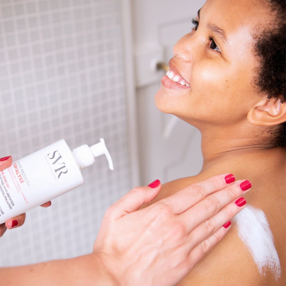 Personne applique de la crème sur l'épaule. Flacon avec logo SVR et nom du produit. Texte: Baume Protect + Topialyse.