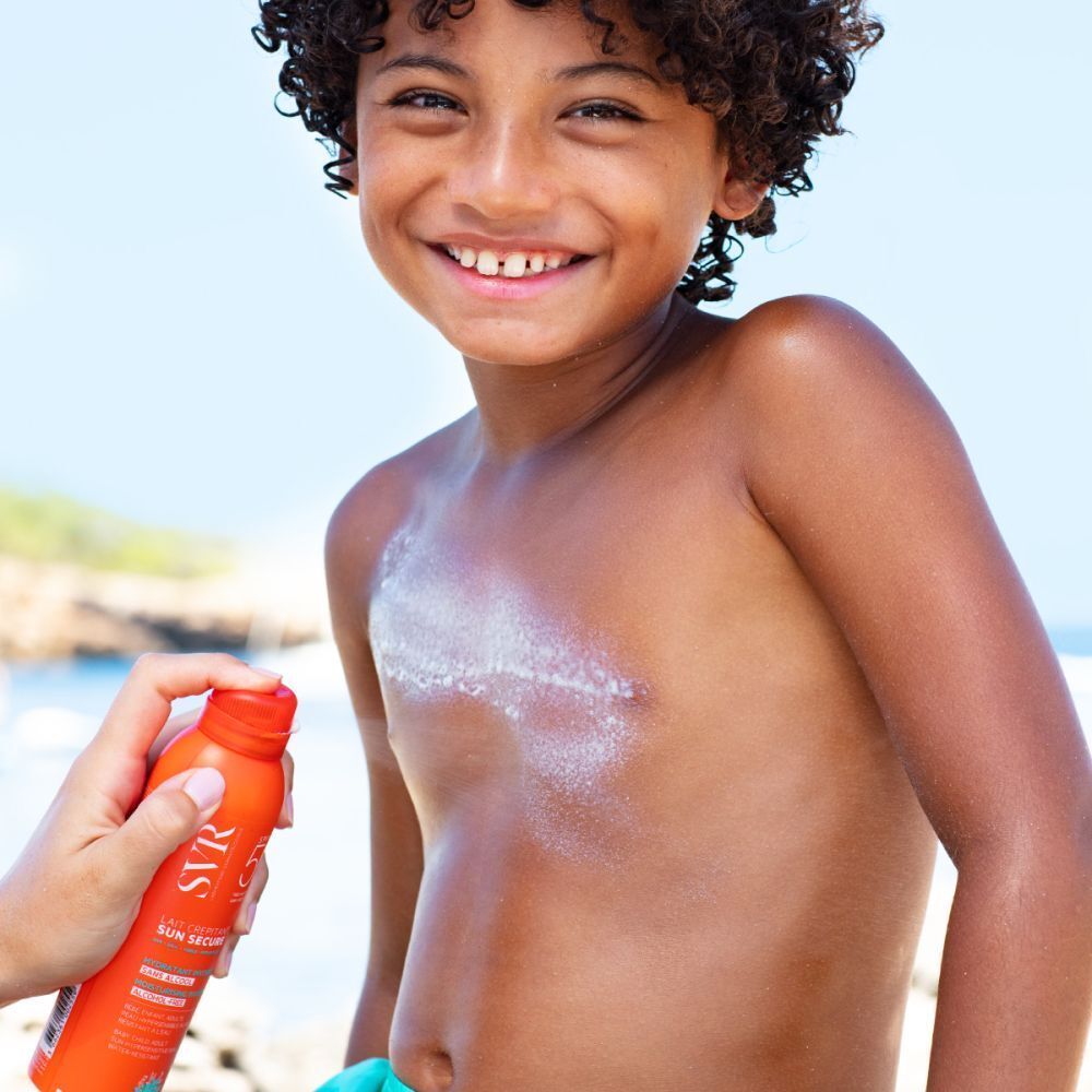 Enfant recevant un spray orange sur la poitrine. Visible: spray, peau.