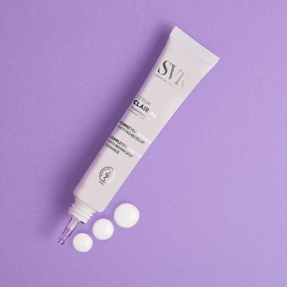 Tube de sérum SVR Clairial et gouttes sur fond violet. Texte: Clairial Serum, Corrector intégral anti-taches éclat.