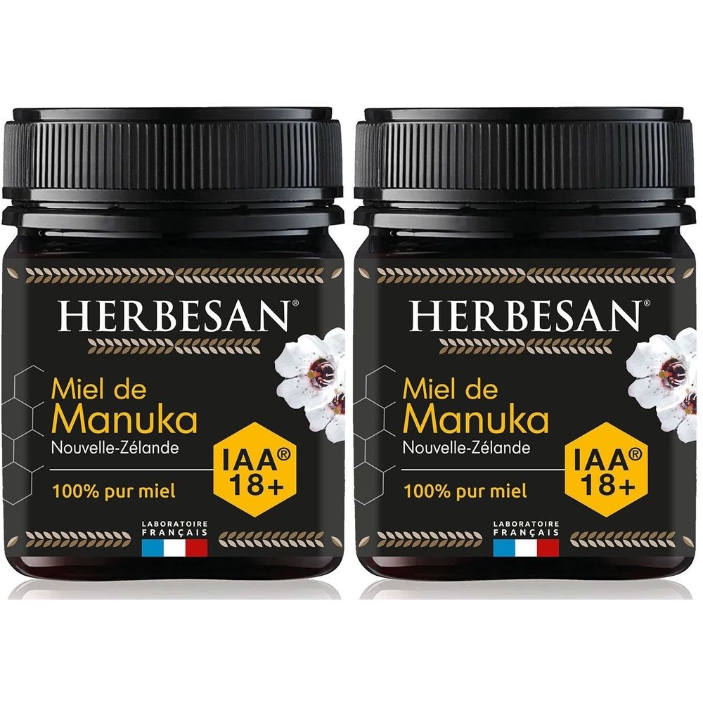 Deux pots de miel HERBESAN Miel de Manuka. Pots noirs avec couvercles noirs. Inscription: IAA 18+ et 100% pur miel.