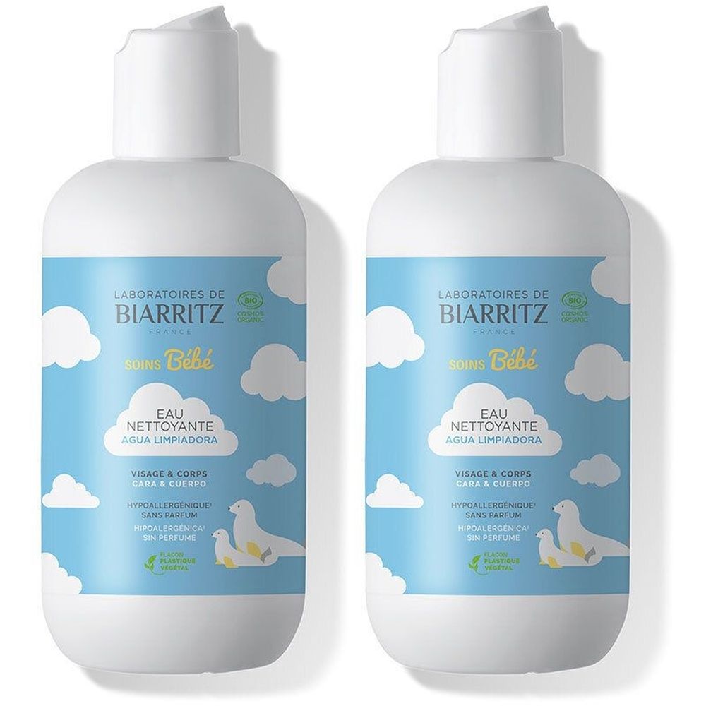Deux flacons de Laboratoires de Biarritz Bébé Eau Nettoyante. Flacons blancs avec étiquette bleue, illustrations de nuages et canards. Texte: Eau Nettoyante.