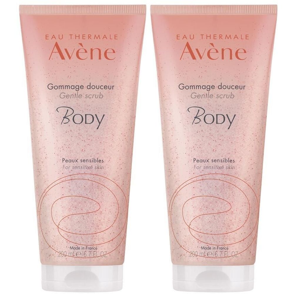 Deux tubes de gommage corporel. Tube rose avec bouchon blanc. Texte: Eau Thermale Avène, Gommage douceur, Body, Peaux sensibles. Fabriqué en France.