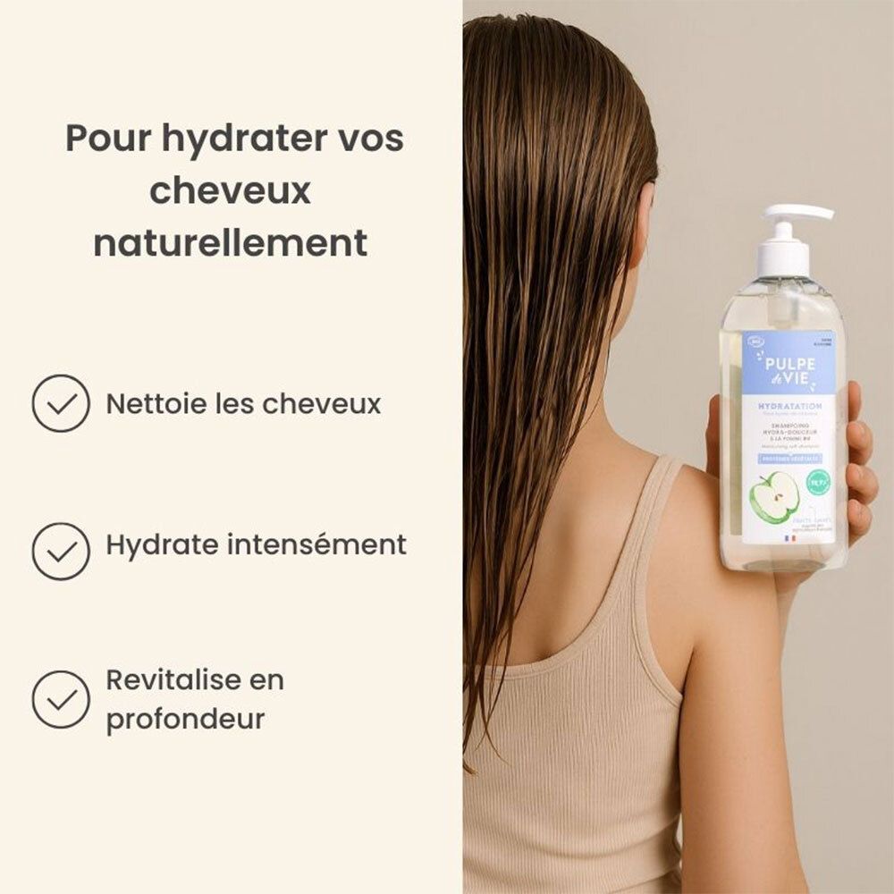 Une personne tient un flacon de shampoing. Sur le flacon, texte et illustration de pomme. Texte : nettoie, hydrate, revitalise.