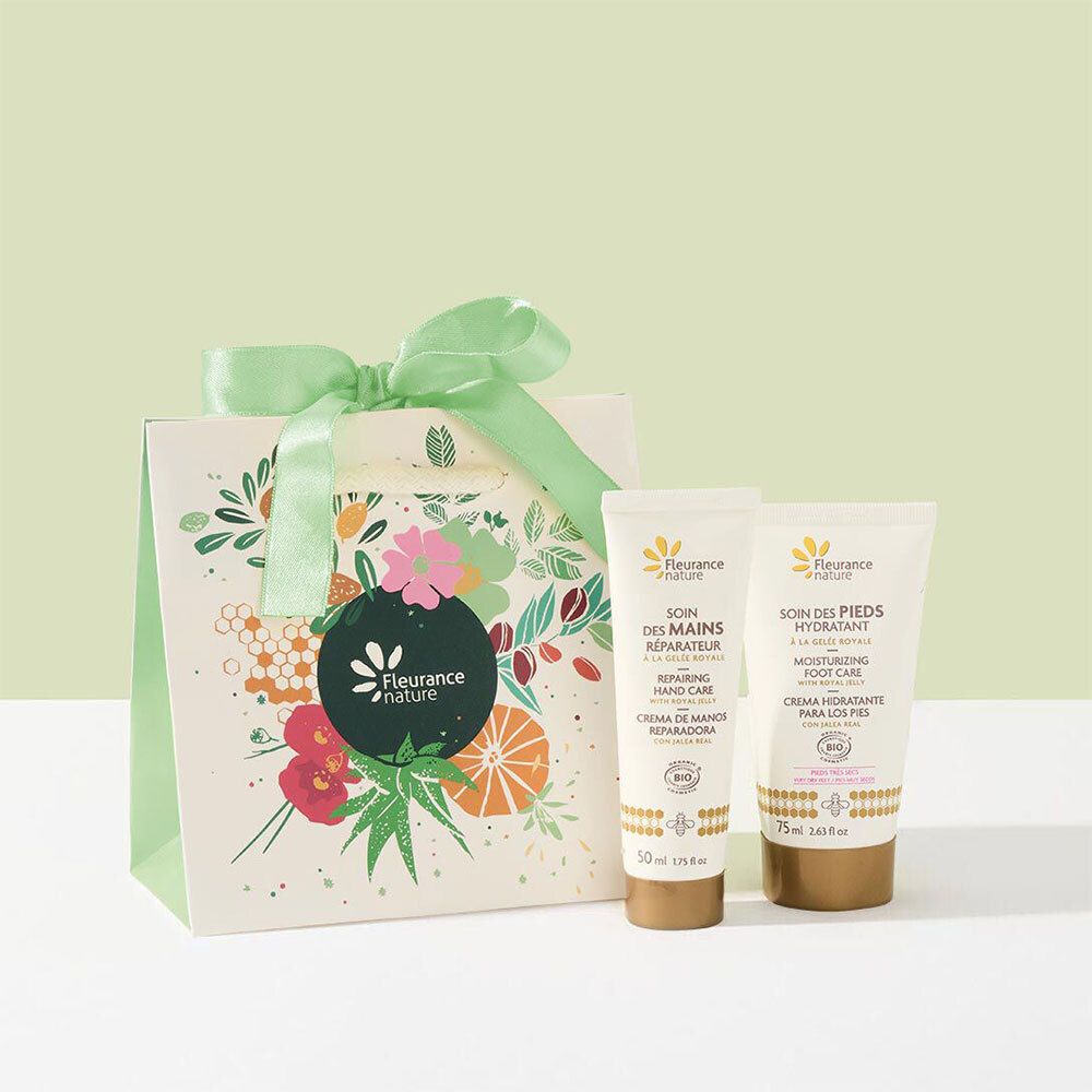 Coffret cadeau avec deux crèmes et un sac. Le sac présente un logo et des motifs floraux. Les crèmes sont conditionnées en tubes.