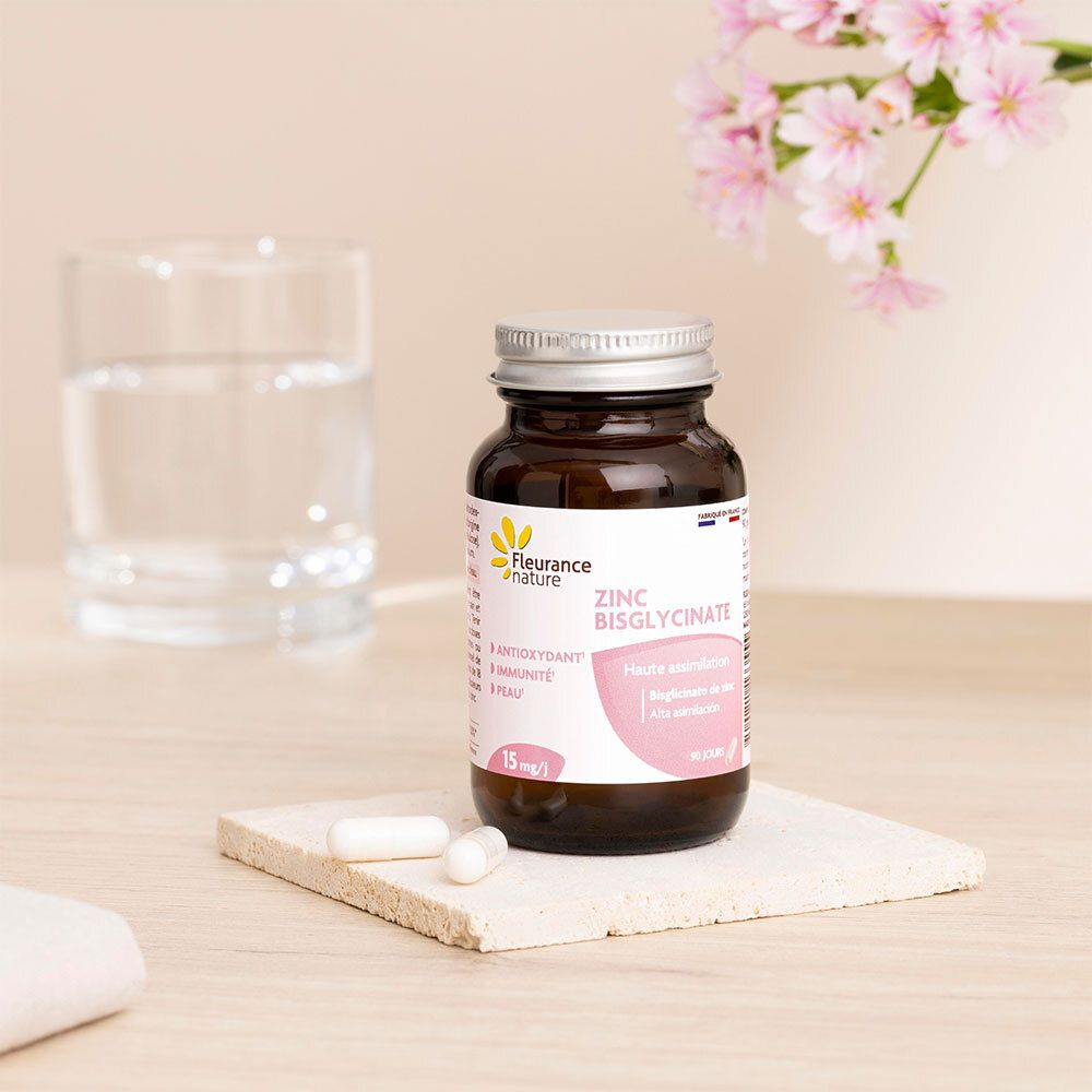 Flacon brun, bouchon argenté et gélules sur une plaque. Verre d'eau et fleurs en arrière-plan. Marque: Fleurance nature.