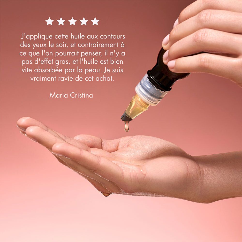 L'huile coule de l'applicateur. Texte: Maria Cristina. Fond rose.
