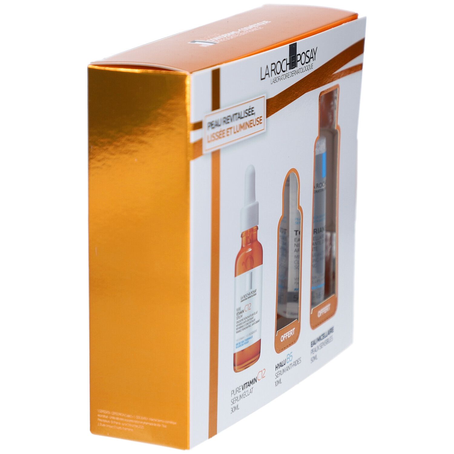 Vue en biais du coffret cadeau. Montre l'emballage avec les noms des produits et le logo de la marque. Éléments dorés et blancs.