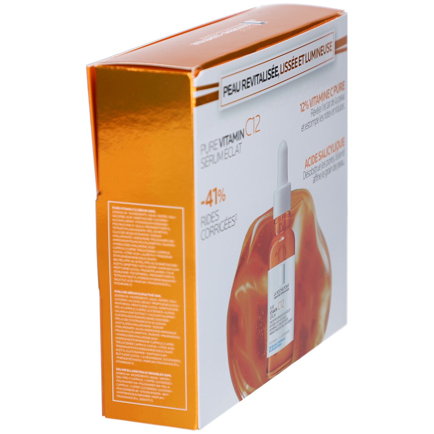 Vue en biais de l'emballage avec flacon de sérum. Affiche les noms des produits et les ingrédients. Fond orange.
