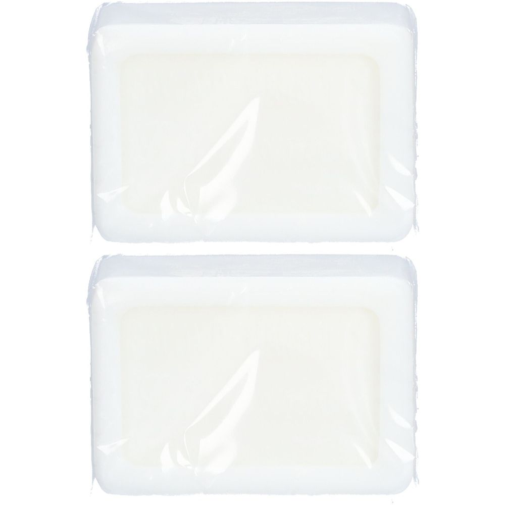 Deux savons rectangulaires emballés dans du film transparent. Les savons sont blancs et ont des bords arrondis.