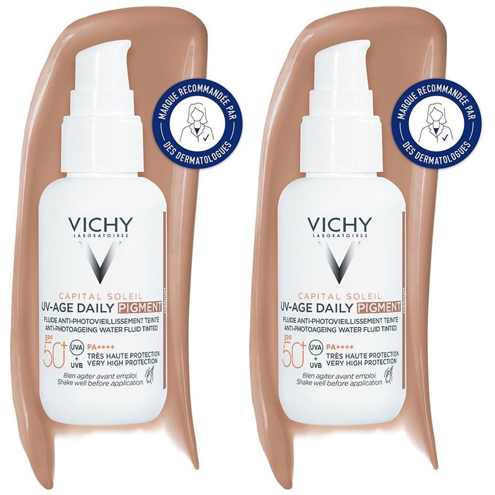 Deux flacons blancs avec pompe. Inscription: VICHY, CAPITAL SOLEIL UV-Age Daily Pigment. Recommandé par des dermatologues. Sur fond de trace de crème teintée.