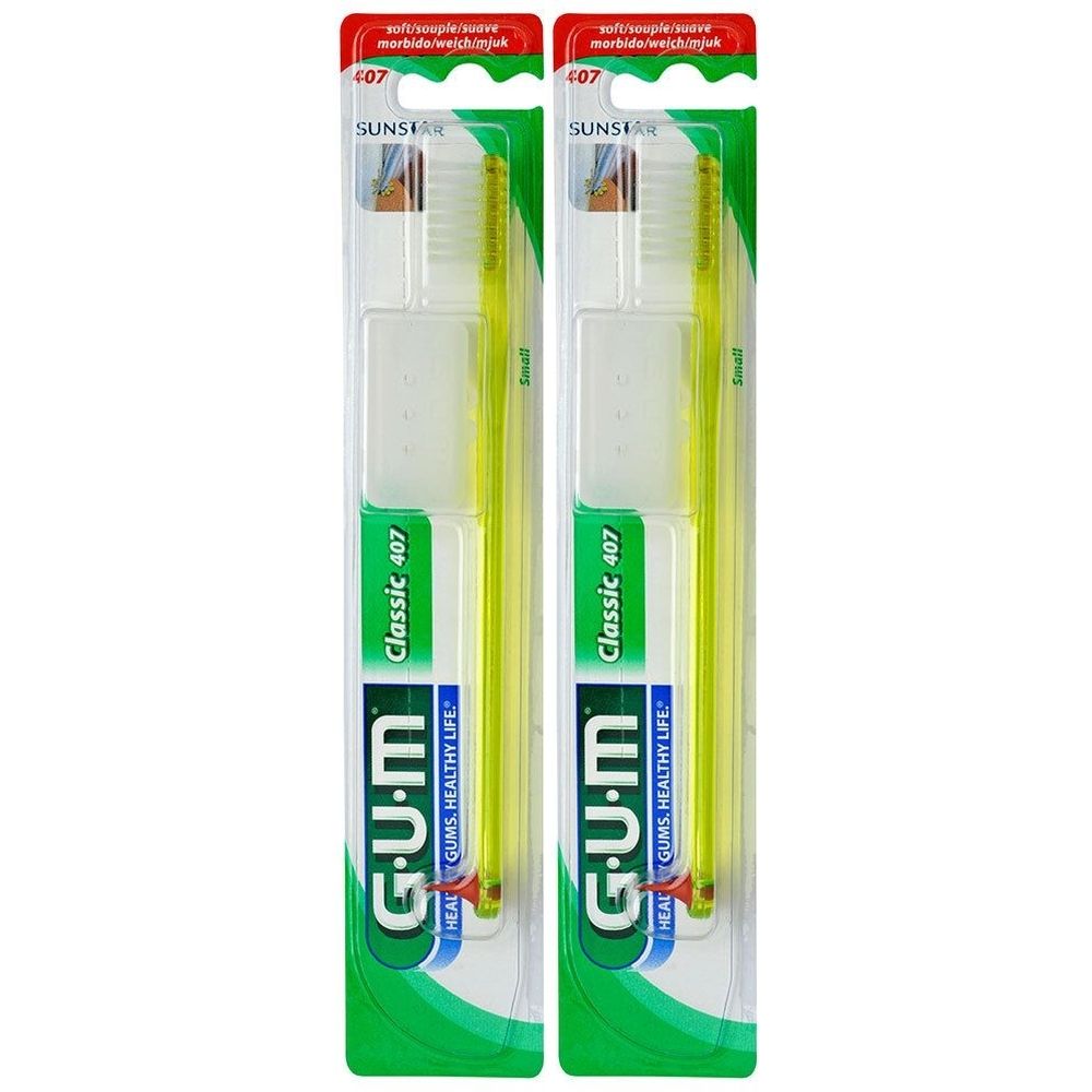 Deux brosses à dents emballées. Manche jaune, tête blanche. Marque G.U.M, modèle Classic 407. Petite tête.