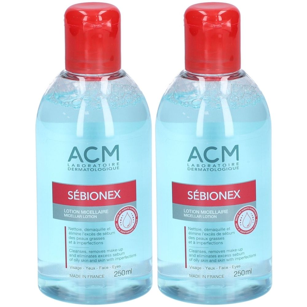 Deux flacons de lotion micellaire ACM Sébionex. Liquide clair dans des flacons transparents avec bouchon rouge. Inscription : Sébionex, 250ml.