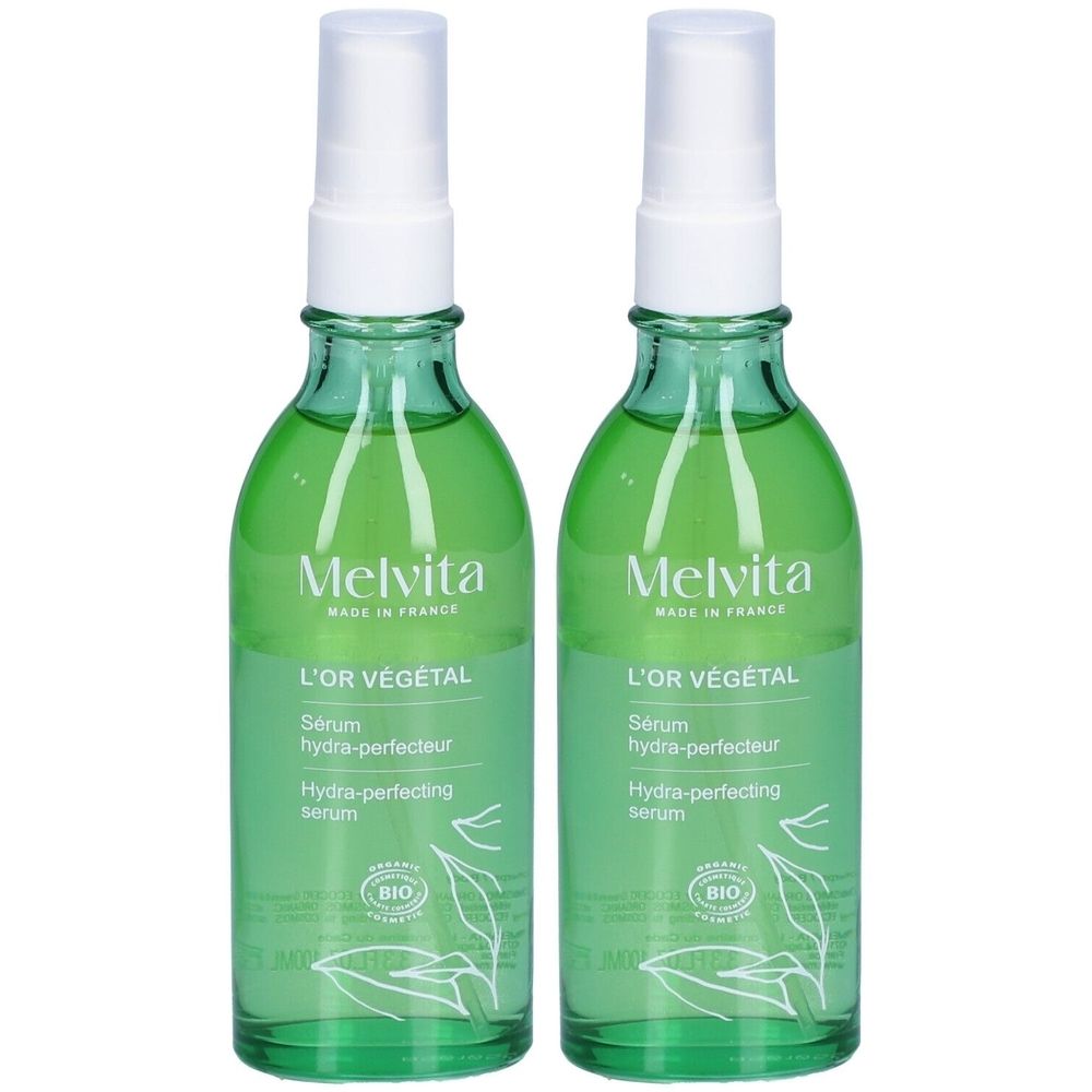 Deux flacons en verre vert avec vaporisateur blanc. Étiquettes: "Melvita L'Or Végétal Sérum Hydra-Perfecteur". Certification Bio.