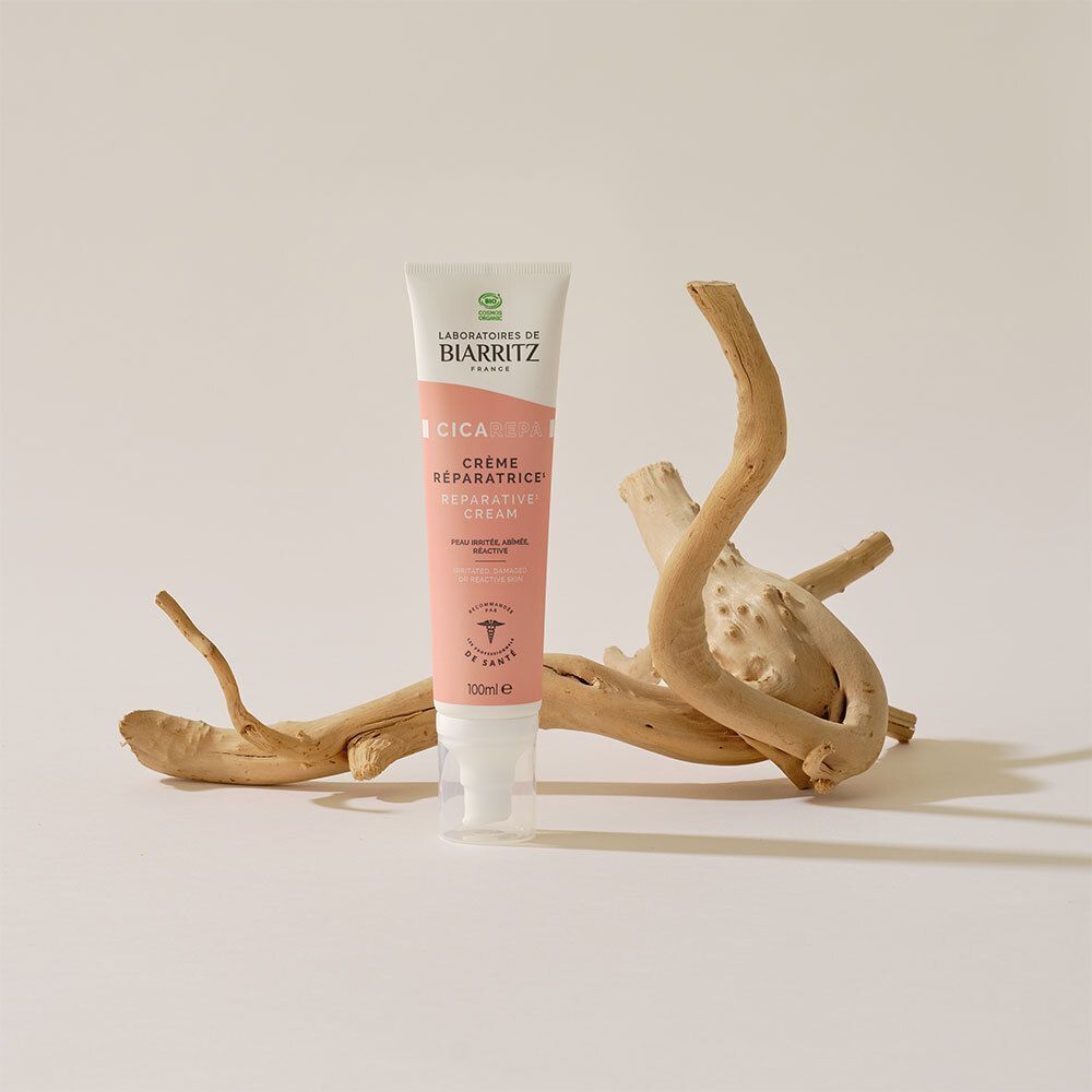 Tube de crème rose et blanche. Inscription CICA REPA, Crème Réparatrice. Mains appliquant la crème sur une cicatrice.