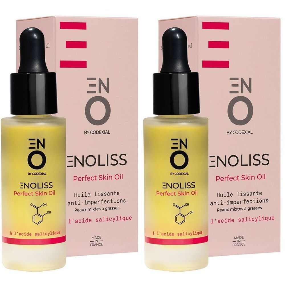 Deux flacons d'huile jaune avec bouchon noir et étiquette. Inscription : ENO Enoliss Perfect Skin Oil. Emballage rose en arrière-plan.