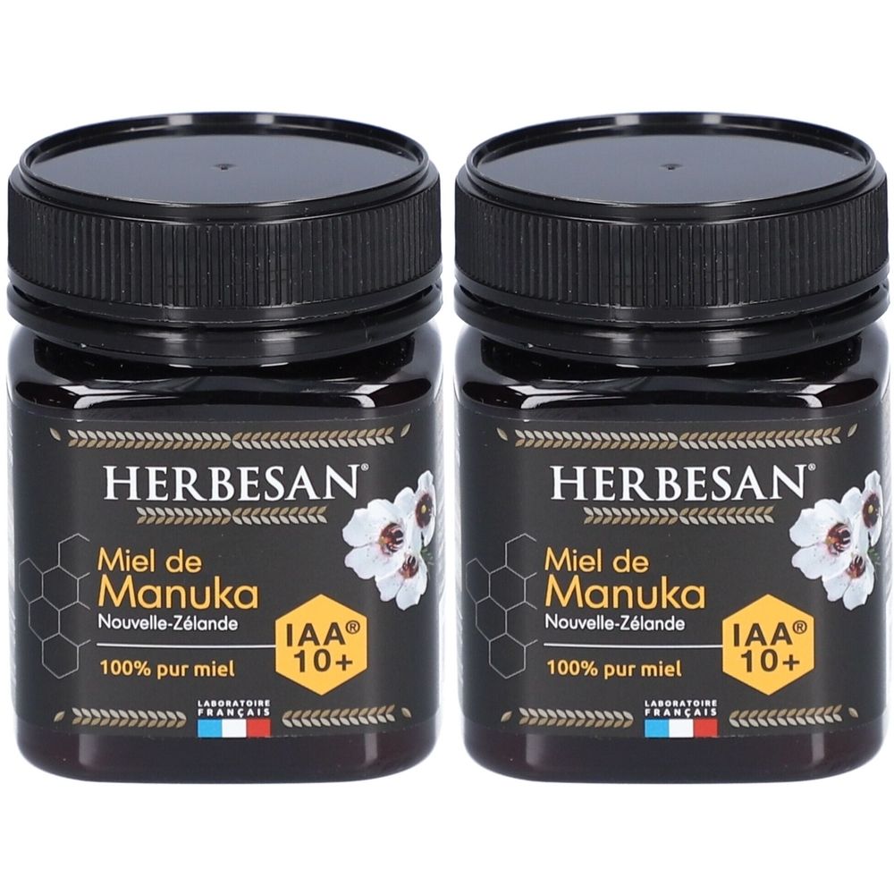 Deux pots de miel Herbesan Miel de Manuka IAA10+. Couvercles noirs, étiquettes avec informations et logo. Drapeau français.