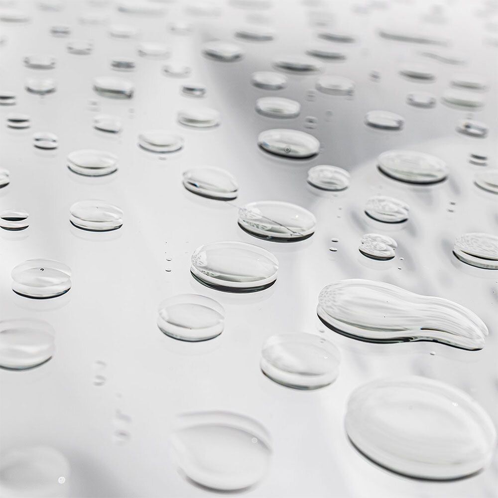 Gros plan de gouttes d'eau sur une surface brillante. Les gouttes sont claires et de tailles variées.