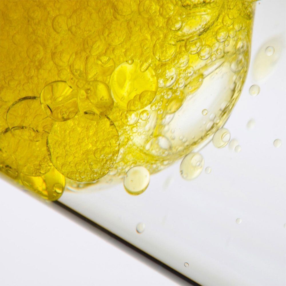 Gros plan de gouttes et bulles de liquide jaune. Liquide dans une bouteille en verre transparente.
