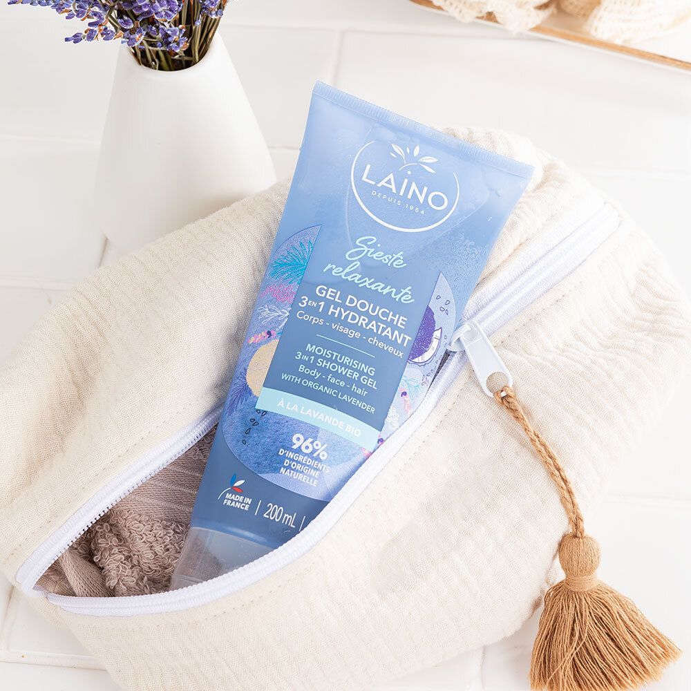 Tube bleu clair avec inscription 'Laino Gel douche 3-en-1 hydratant' dans une trousse de toilette ouverte.