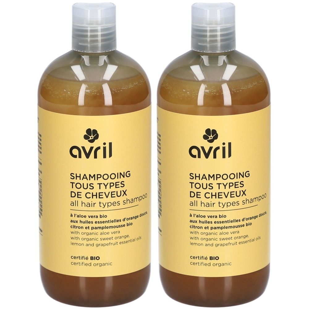 Deux flacons de shampooing Avril. Étiquettes jaunes avec texte: Shampooing Tous Types de Cheveux, certifié Bio. Contient aloe vera.