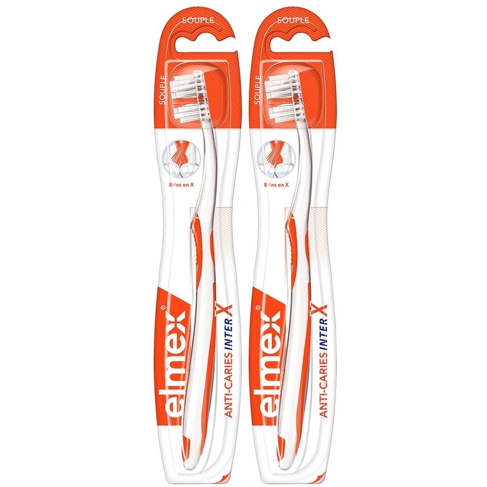 Deux brosses à dents dans un emballage orange. Inscription: elmex ANTI-CARIES INTER X. Soie souple. Trou de suspension.