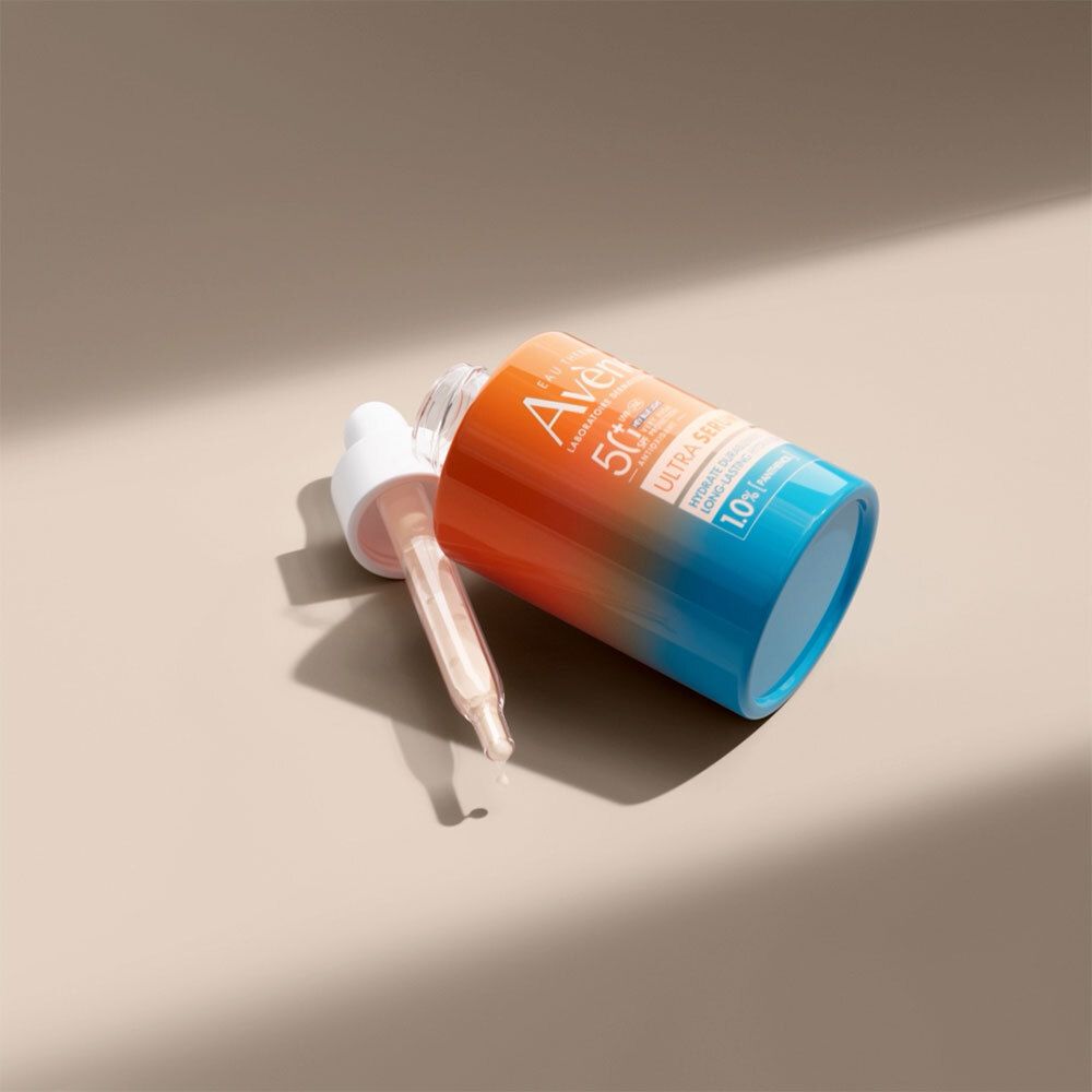 Flacon de sérum et pipette. Dégradé orange et bleu. Inscription : Avène, Ultra Serum SPF50+, 1,0% Panthénol.