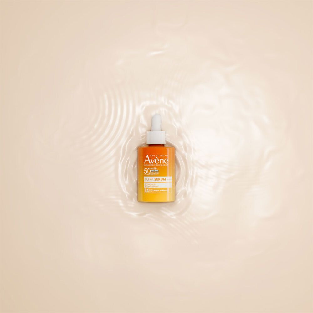 Flacon orange avec compte-gouttes blanc dans l'eau. Inscriptions : Eau Thermale Avène, SPF 50+, Ultra Serum.