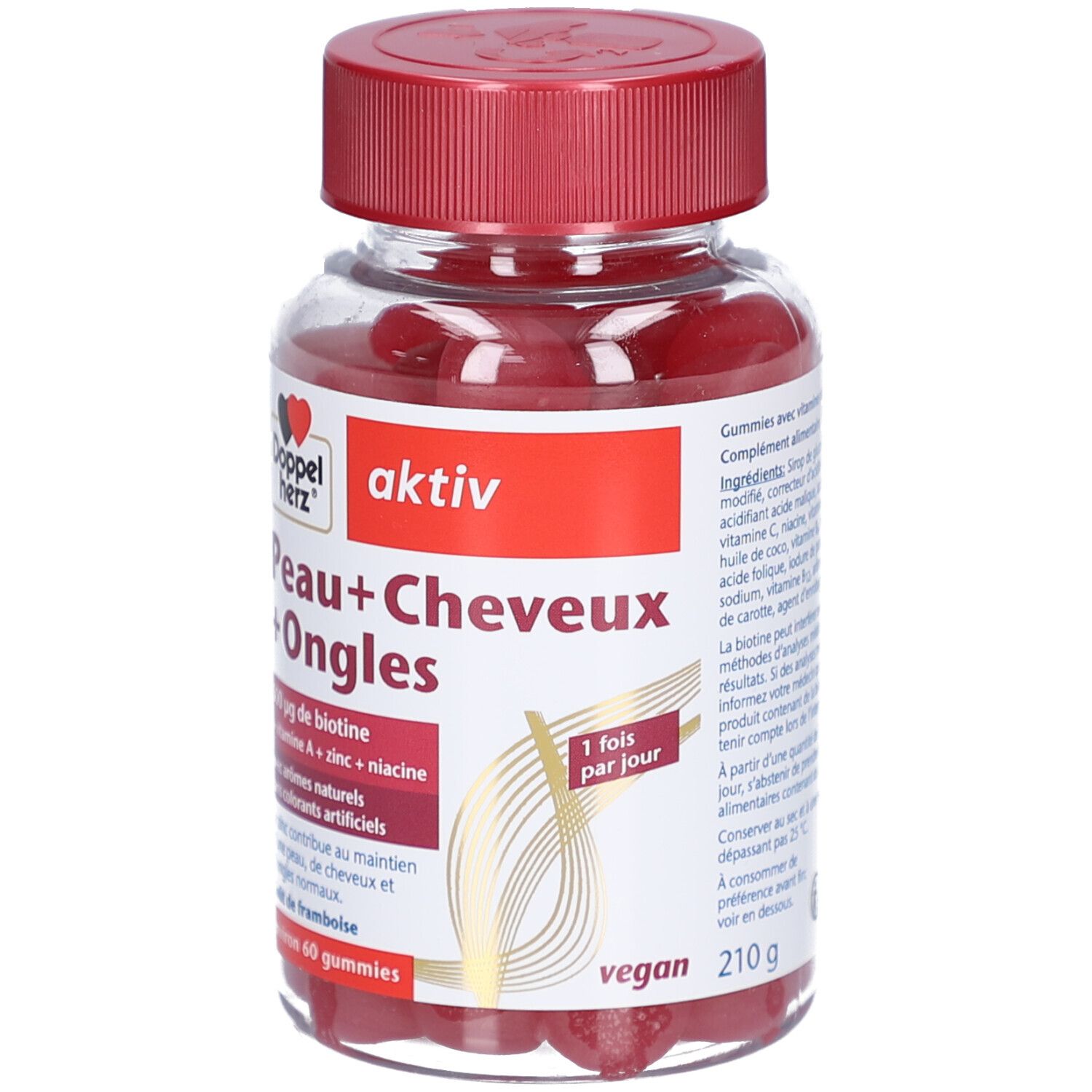 Flacon transparent avec bonbons rouges. Bouchon rouge. Inscription: Peau+Cheveux+Ongles, actif, 500 µg biotine, vegan, 210 g.