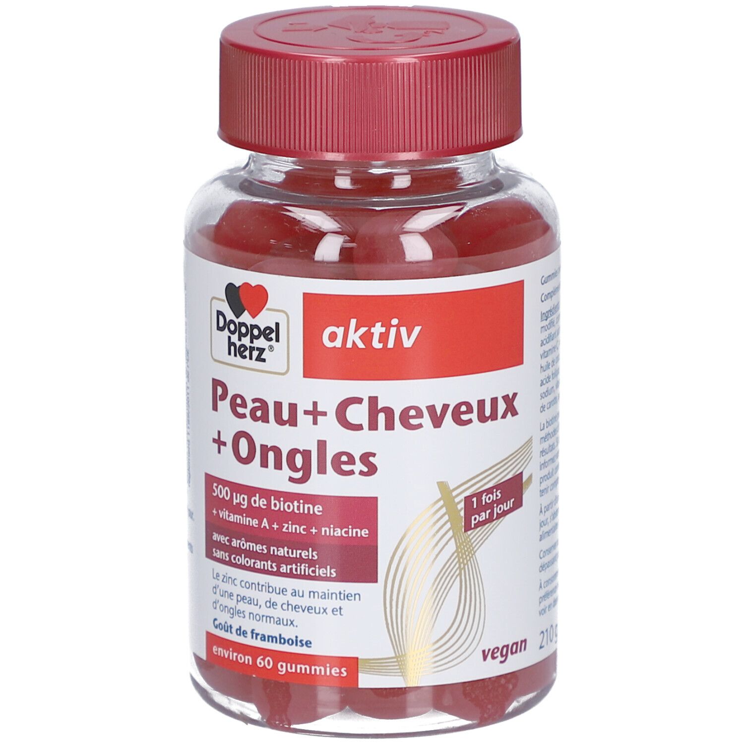 Flacon transparent avec bonbons rouges. Bouchon rouge. Inscription: Peau+Cheveux+Ongles, actif, 500 µg biotine, vegan.