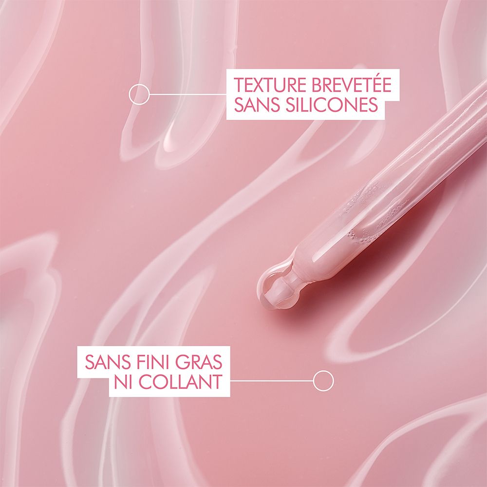 Gros plan du sérum sur surface rose. Texte : Sans silicones, non gras.