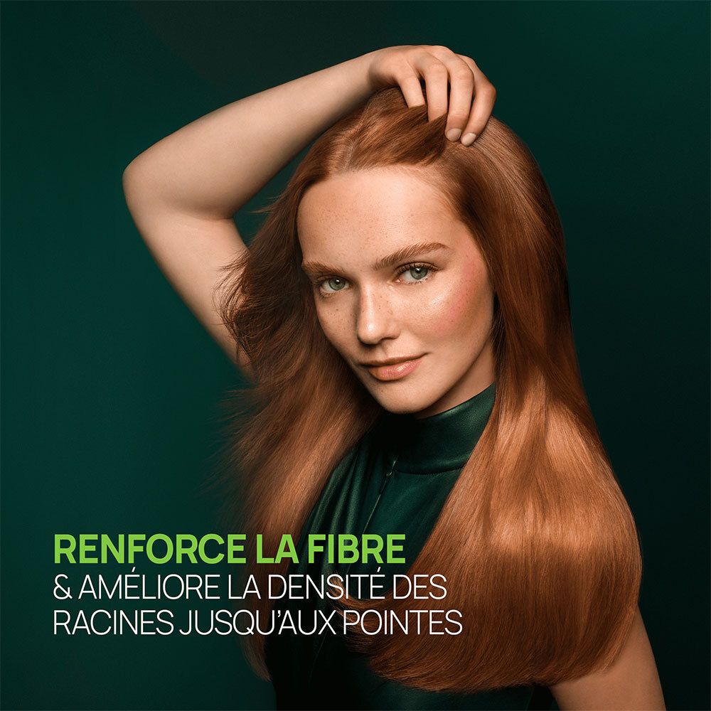 Femme aux cheveux roux touchant son cuir chevelu. Texte : Renforce la fibre et améliore la densité.