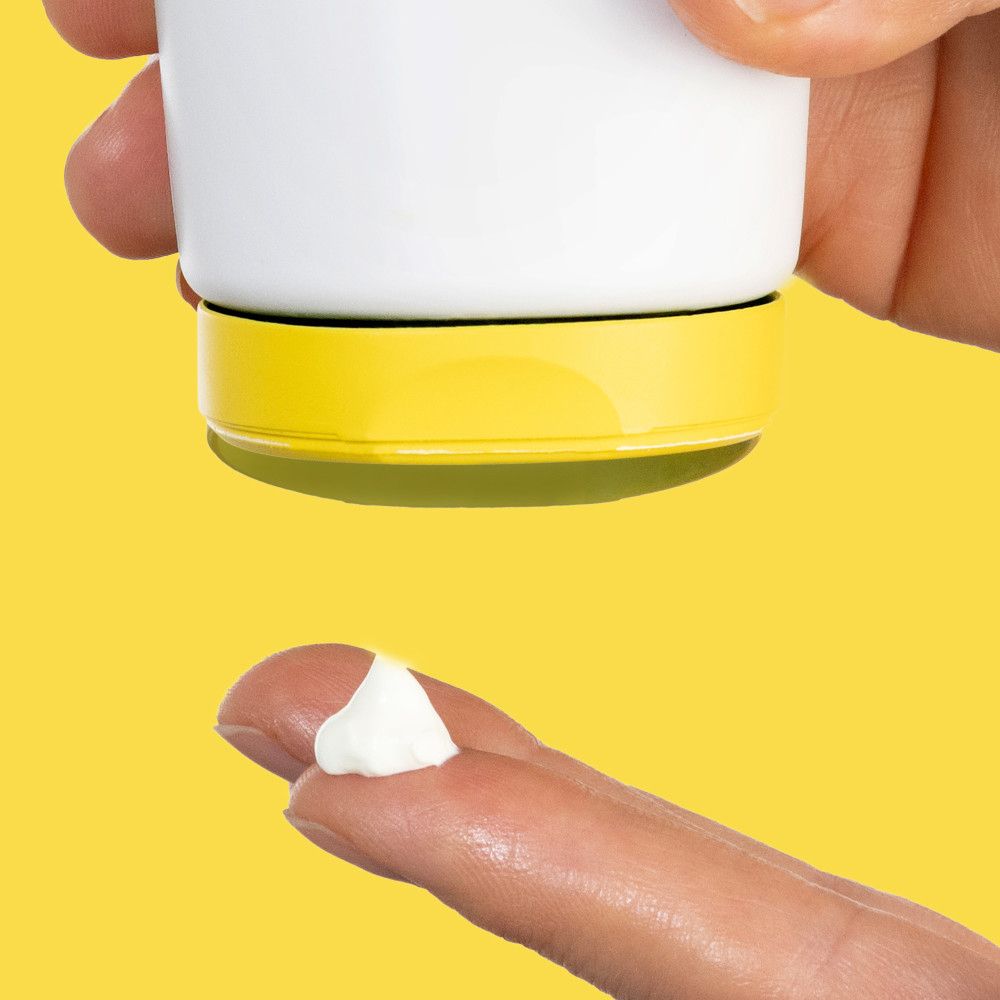 Application du produit sur un doigt. Fond jaune. Texture crème.