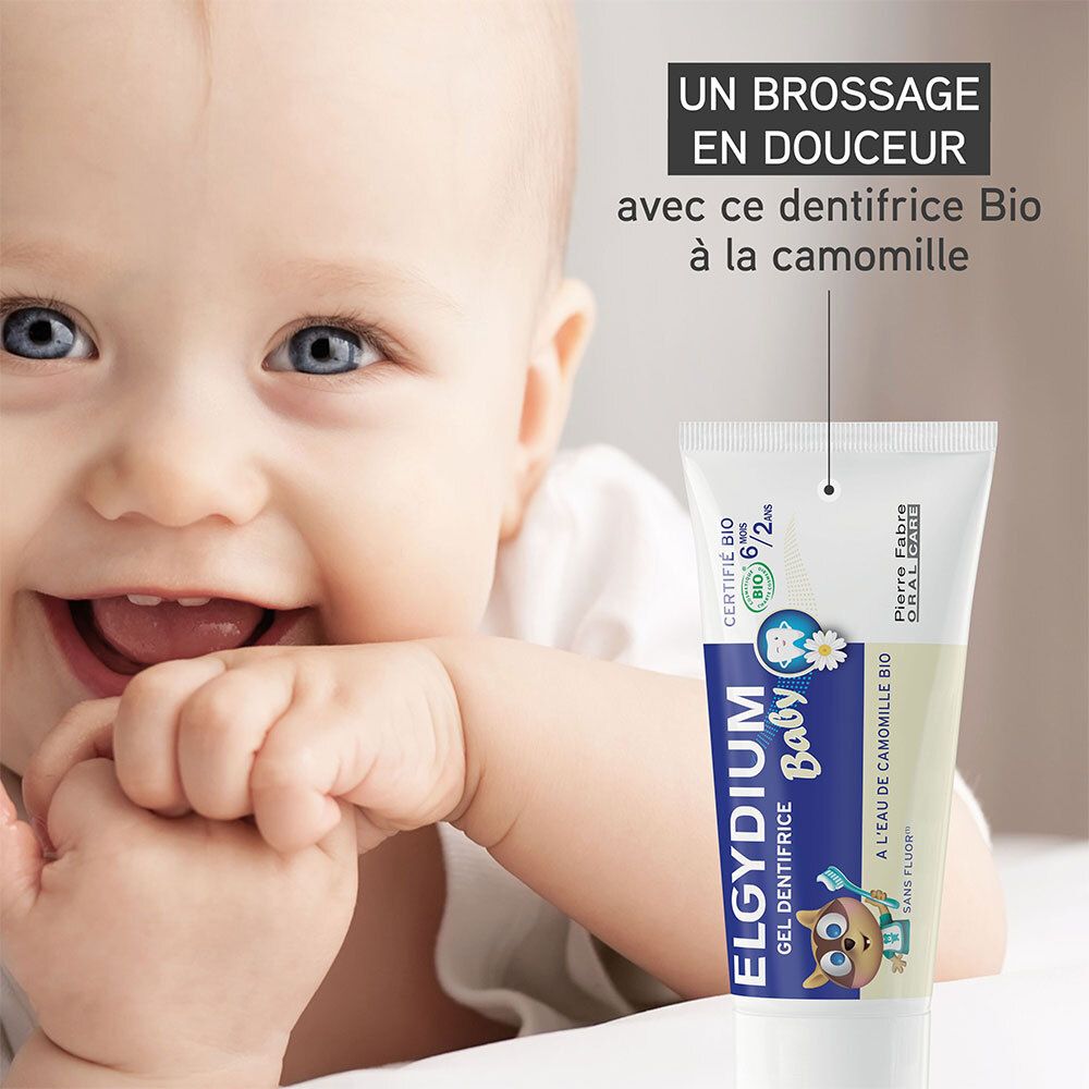 Bébé sourit. À côté, tube ELGYDIUM Baby. Texte : Un brossage en douceur avec ce dentifrice Bio à la camomille.
