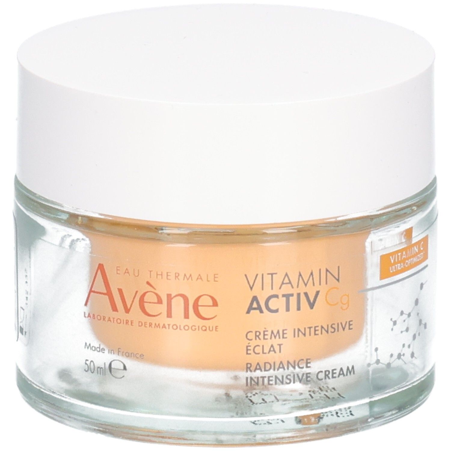 Pot en verre avec couvercle blanc. Inscription: Avene, Vitamin Activ Cg, Crème Intensive Eclat, Radiance Intensive Cream. Contenu orangé.