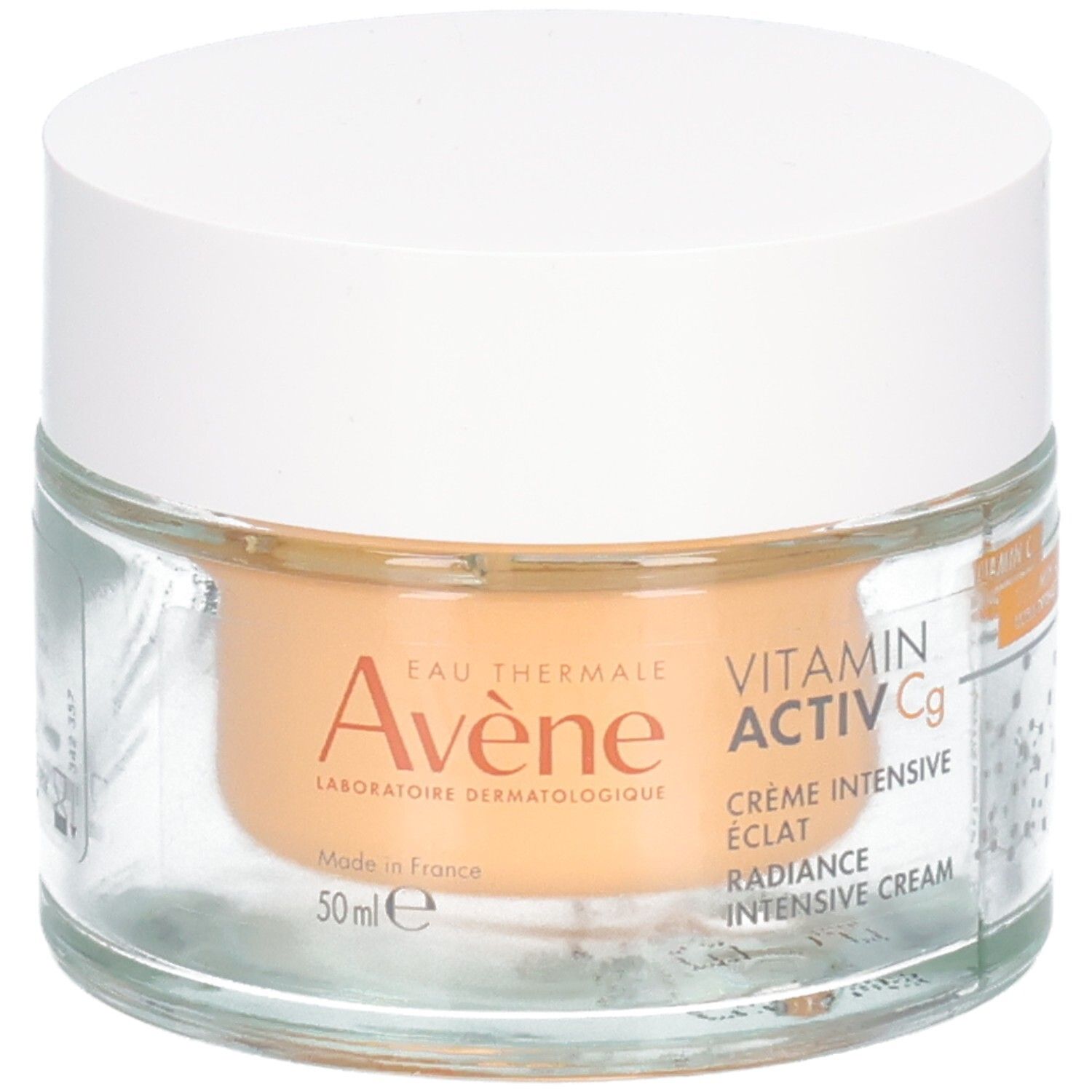 Pot en verre avec couvercle blanc. Inscription: Avene, Vitamin Activ Cg, Crème Intensive Eclat, Radiance Intensive Cream. Contenu orangé.