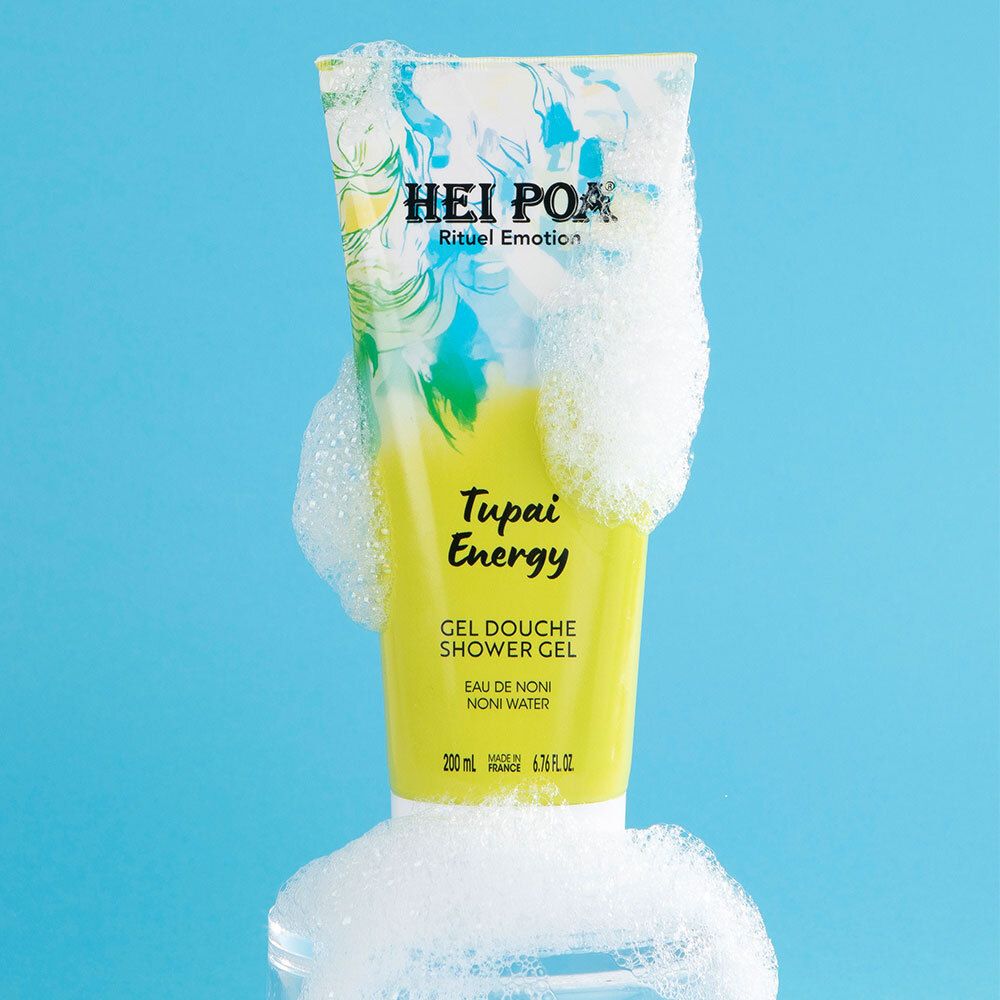 Tube de gel douche Hei Poa Tupai Energy dans de la mousse et des bulles sur fond bleu.