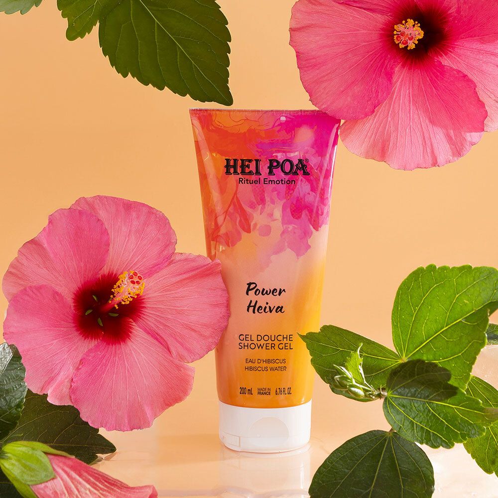 Tube Hei Poa Gel Douche Power Heiva entouré de fleurs d'hibiscus et de feuilles.