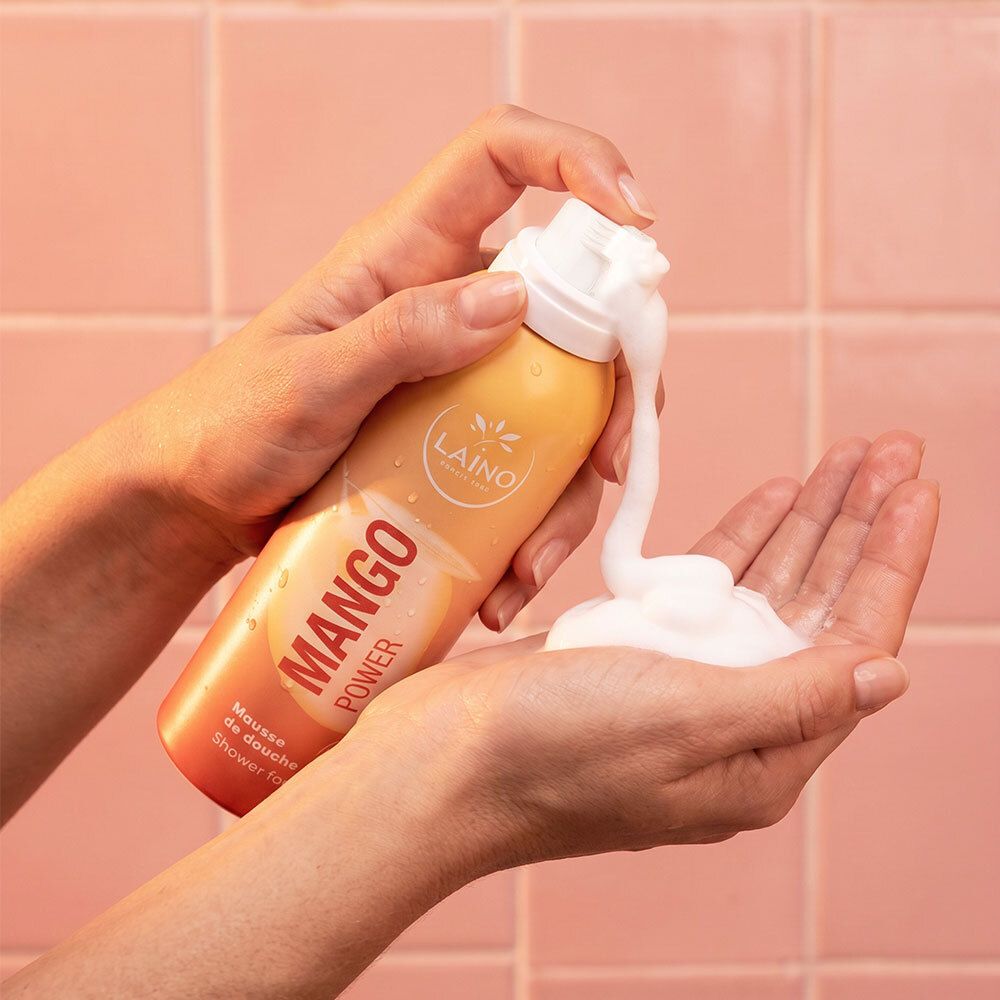 Mains pressant la mousse de douche LAINO Mango Power dans une paume.