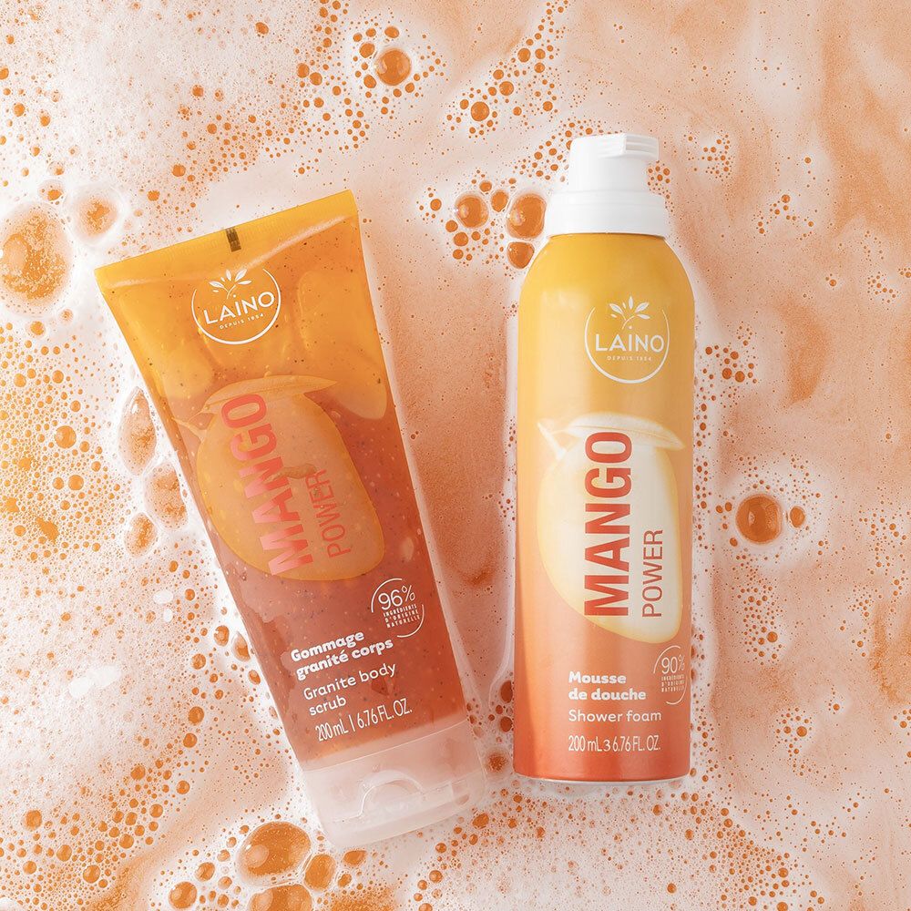 Gommage corps et mousse de douche Laino Mango Power côte à côte dans de l'eau moussante.