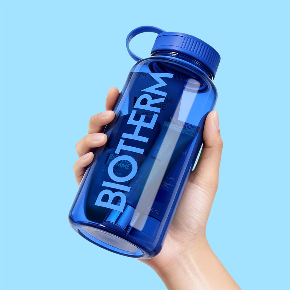 Main tenant une gourde bleue Biotherm avec des produits de soin.