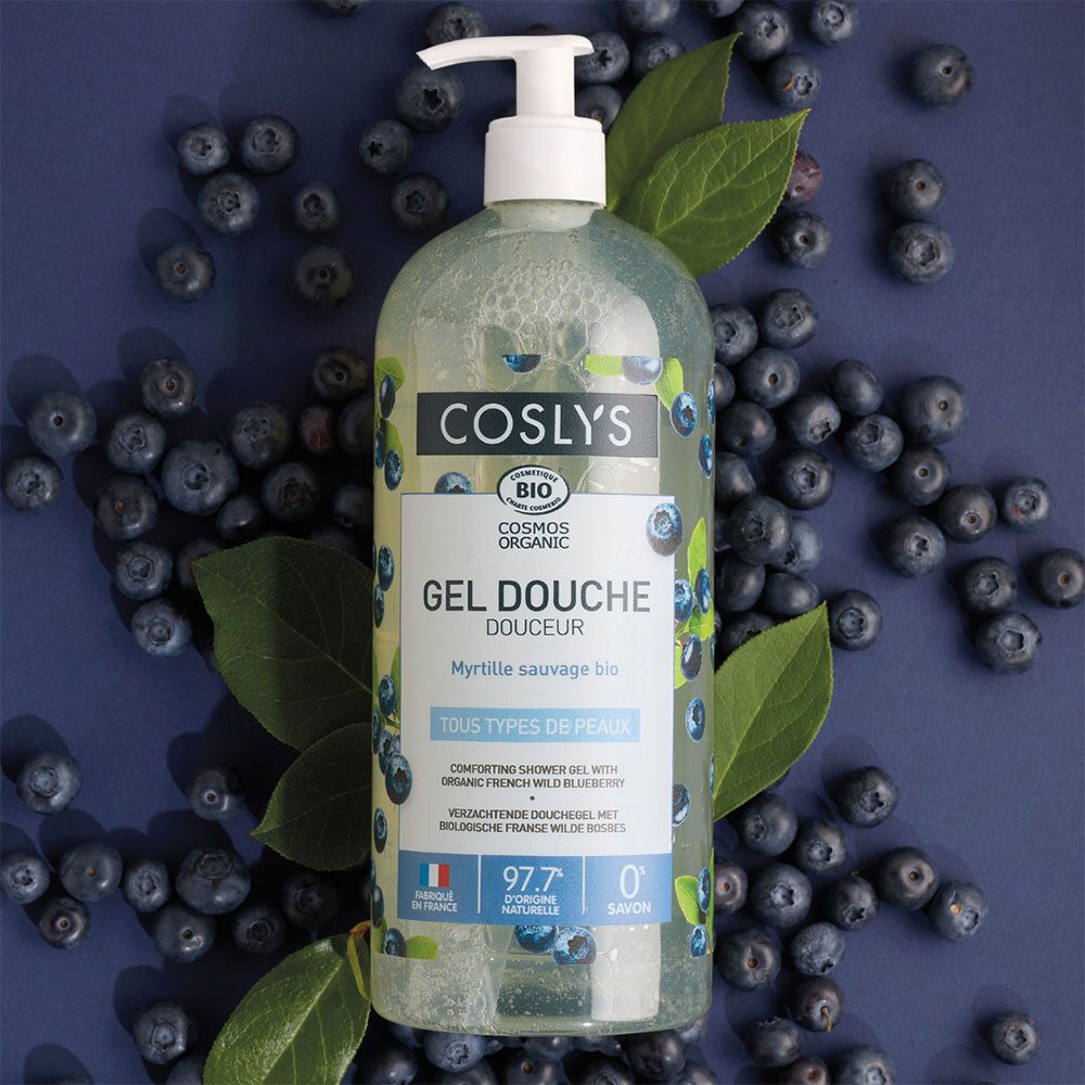 Flacon de gel douche Coslys avec pompe, entouré de myrtilles et de feuilles. Étiquette avec informations produit.