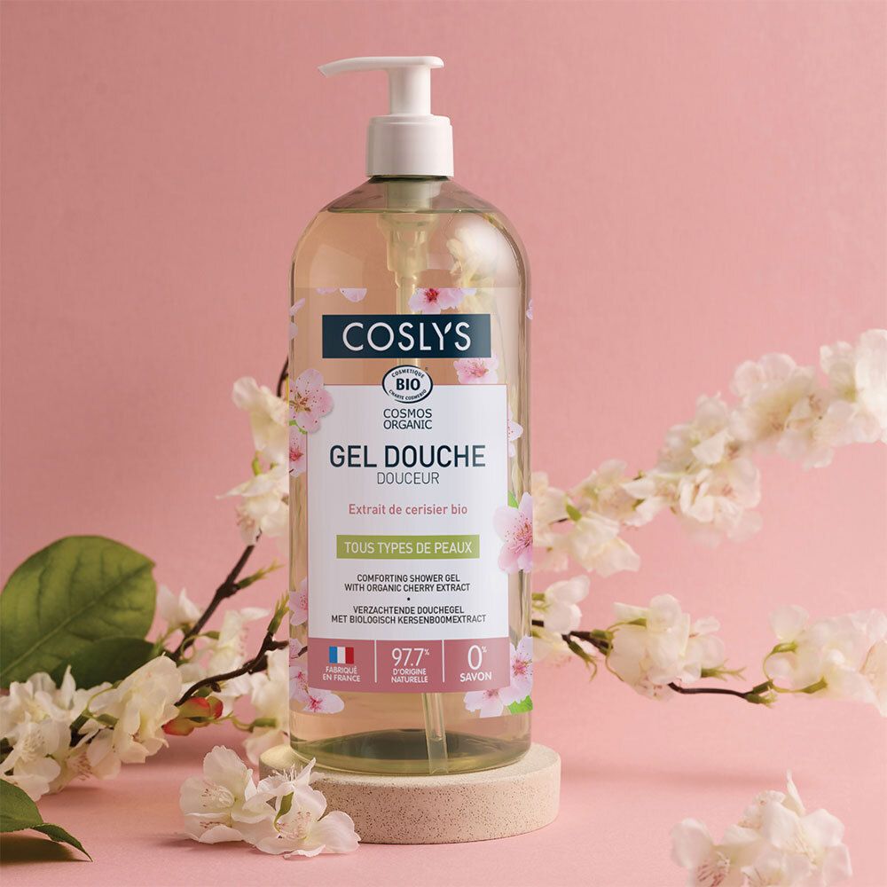 Flacon de produit sur socle, entouré de fleurs de cerisier. Étiquette avec nom du produit et certification bio.