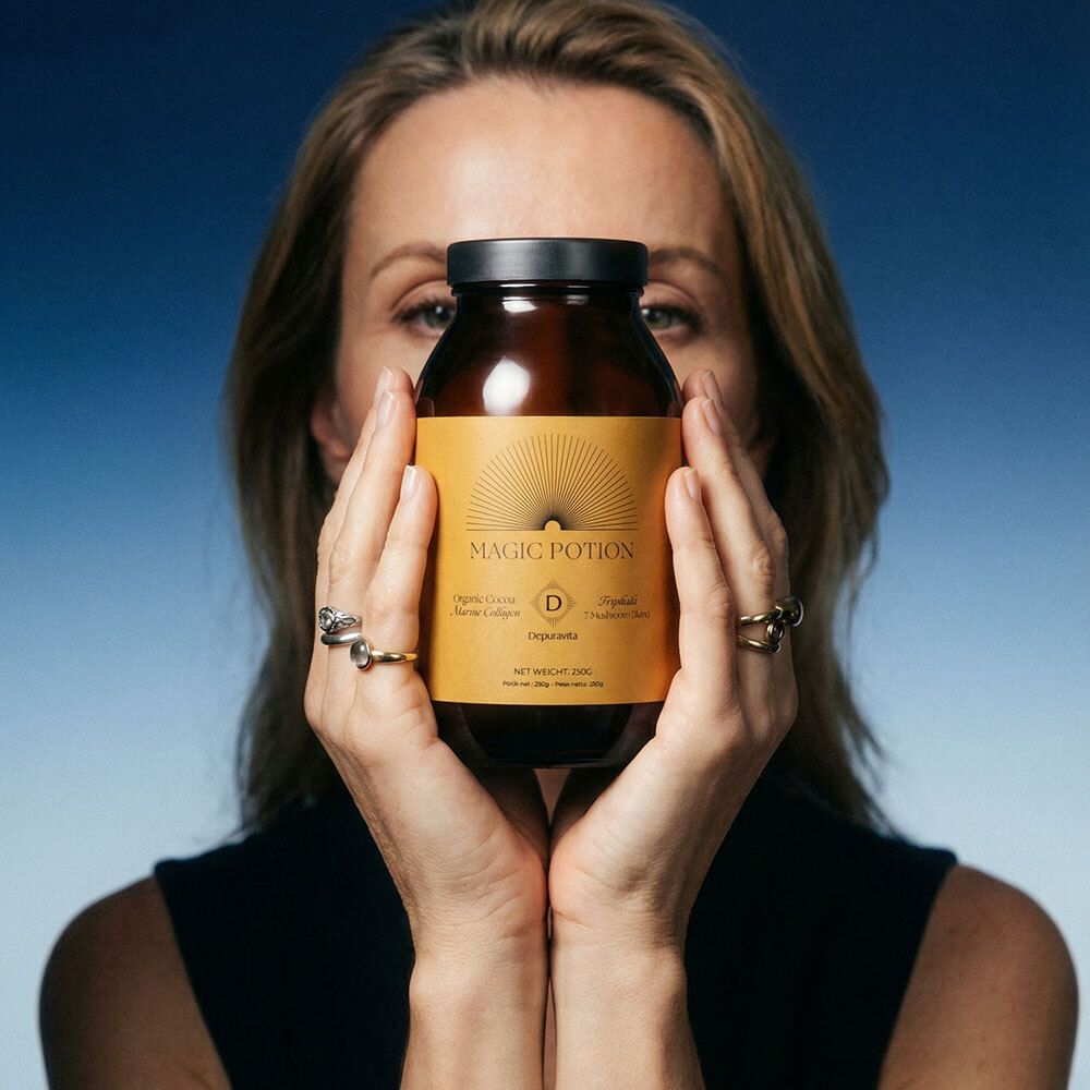 Femme tenant une bouteille marron avec une étiquette jaune devant son visage. Inscription : Magic Potion, Depuravita.