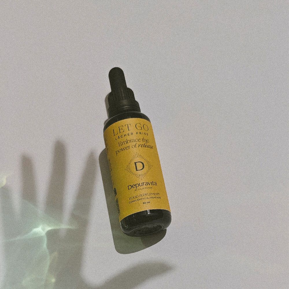 Flacon en verre brun avec bouchon noir et pipette. Étiquette dorée avec texte: LET GO, Depuravita. Produit.