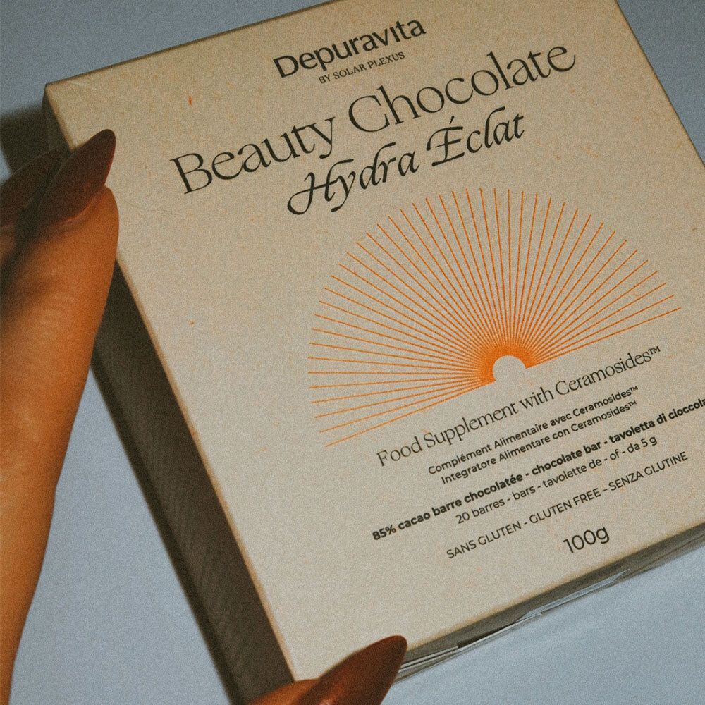 Gros plan d'une main tenant une boîte de Depuravita Beauty Chocolate.
