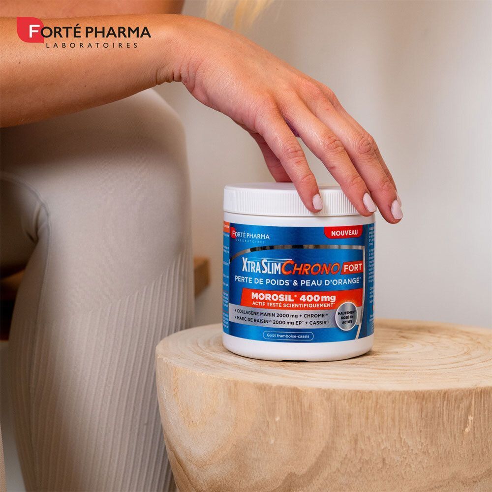 Personne tient boîte XtraSlim Chrono Fort. Boîte blanche avec étiquette bleu-orange. Posée sur un bloc de bois.