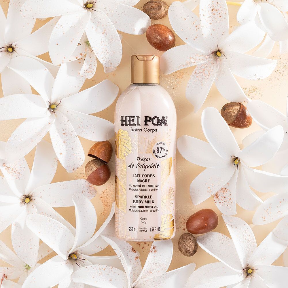 Flacon avec bouchon doré, entouré de fleurs blanches et noix. Inscription: HEI POA, Soins Corps, Trésor de Polynésie, Lait Corps Nacré, Sparkle Body Milk.