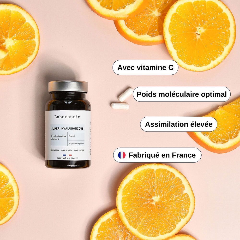 Un flacon noir avec couvercle argenté. Étiquette "Laborantin Super Hyaluronique". Tranches d'orange et gélules à côté.
