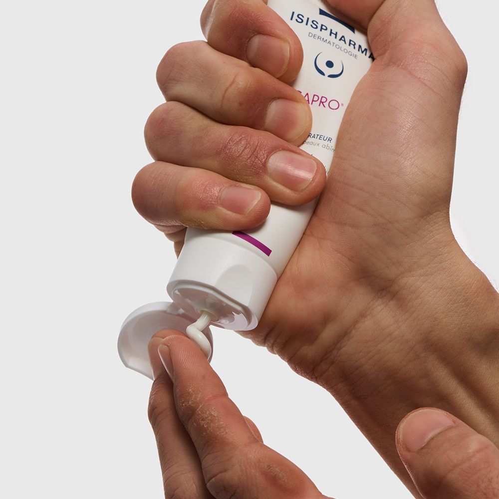 Main pressant de la crème du tube. Crème blanche. Fond neutre.